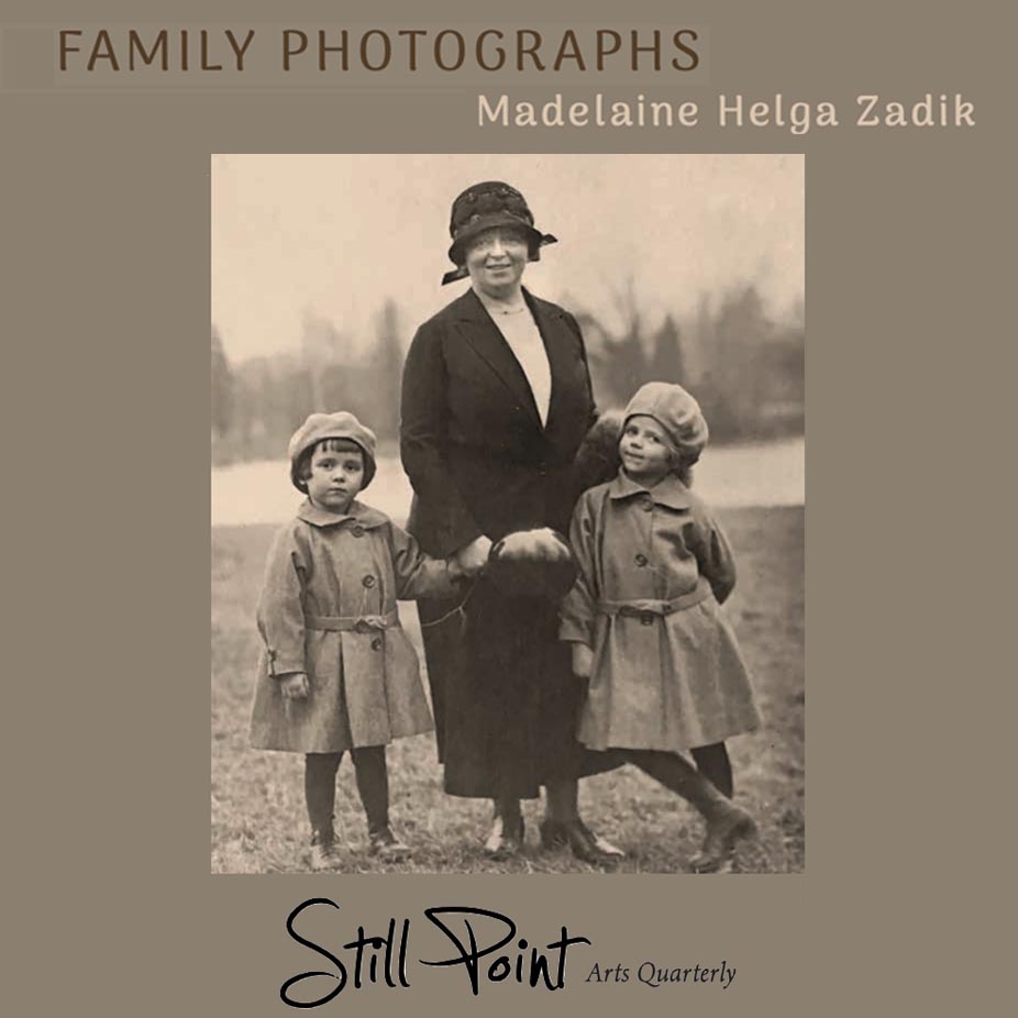 Photograph of mother with two daughters by her side, all wearing coats and hats, with a river behind them.